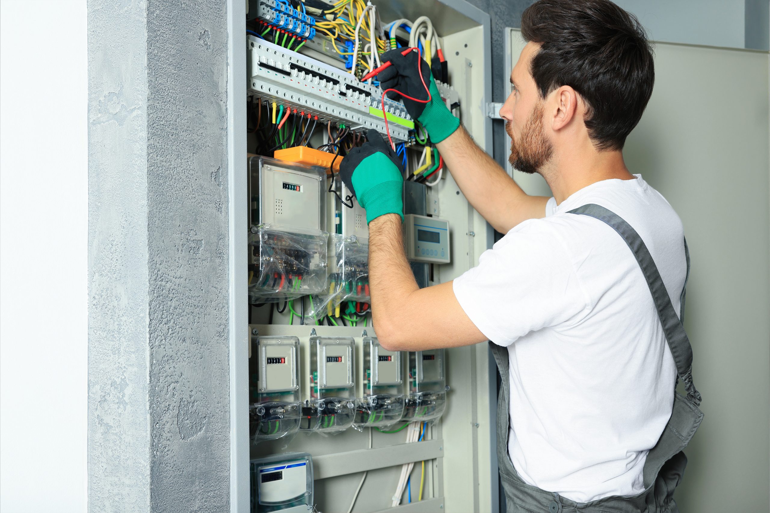Elektronier_in Elektroniker arbeitet an einem Schaltschrank.