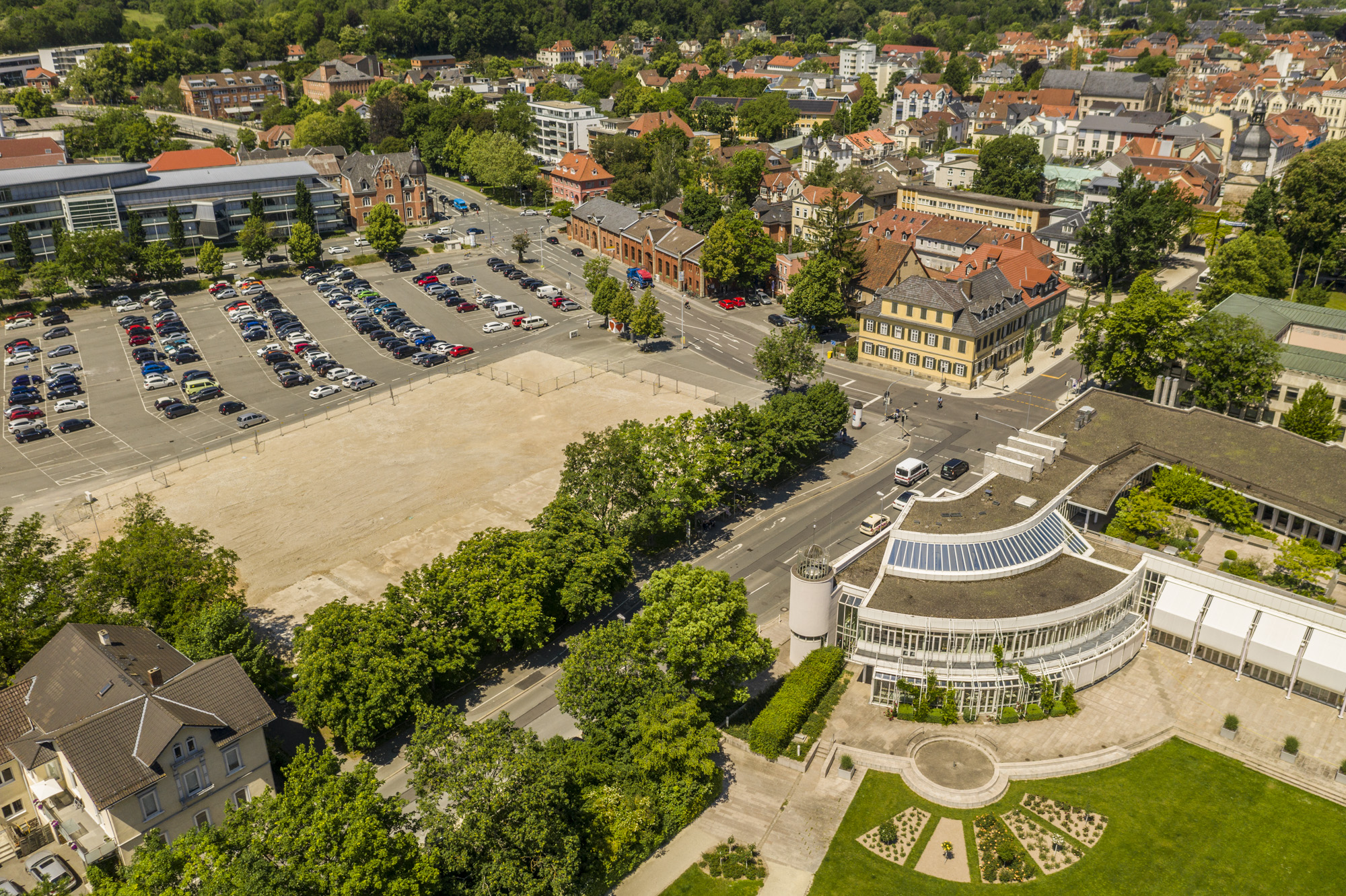 Großparkplatz mit parkenden Autos, anliegender Straße, Freifläche und Kongresshaus Rosengarten.
