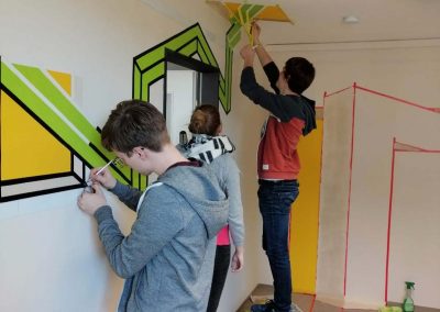 Studenten der Hochschule Coburg, die eine Wand bunt bemalen.