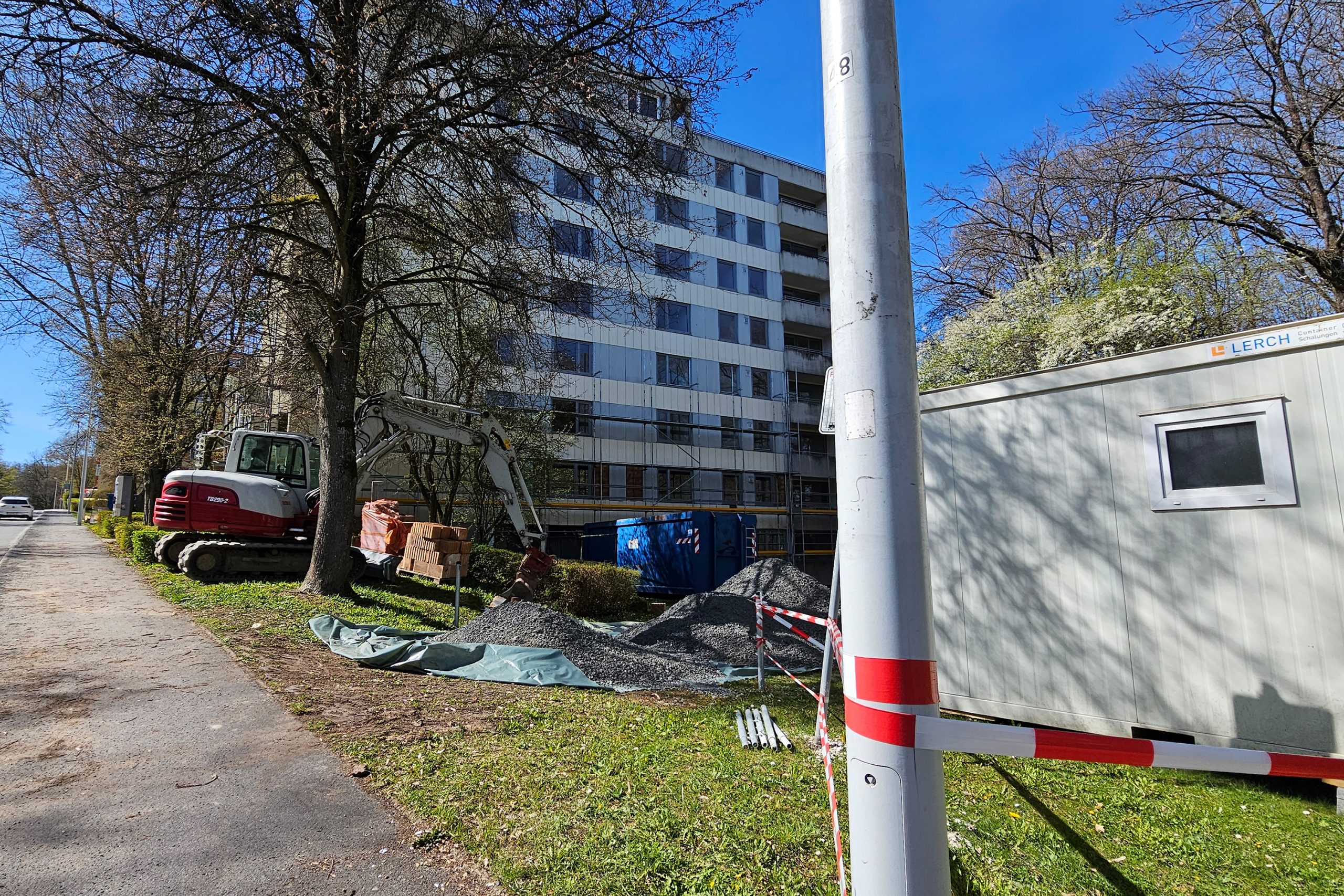Baustelle Heimatring 53 Gebäude mit halb hohem Gerüst und Baustellencontainern davor.