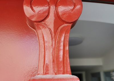 Verschnörkeltes Detail einer roten Eingangstür.