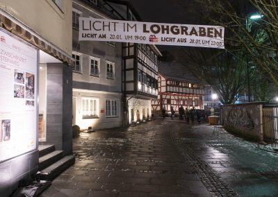 Straße mit beleuchteten Gebäuden und Banner.