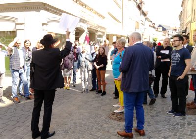 Gruppe mit Stadtführer, der ein Bild hochhält.