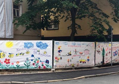 Bemaltes Banner an einem Bauzaun.