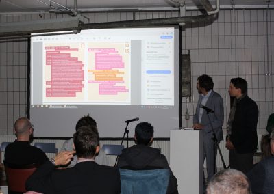 Redner neben einer Leinwand mit Präsentation.